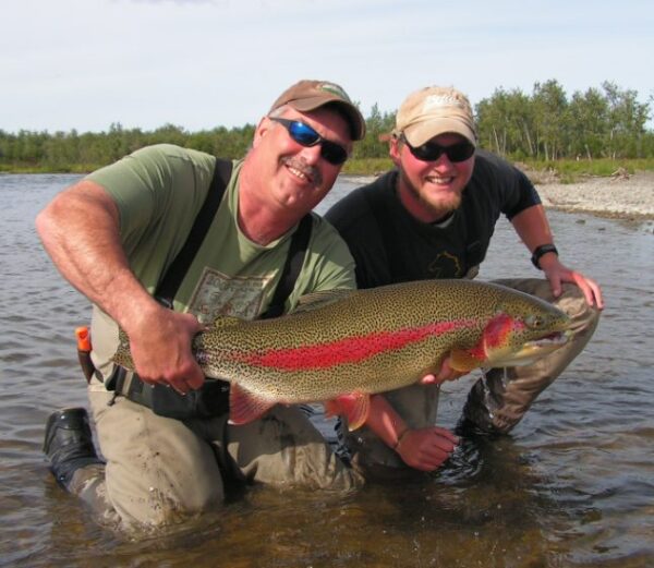 Two anglers with a trophy rainbow trout in the river